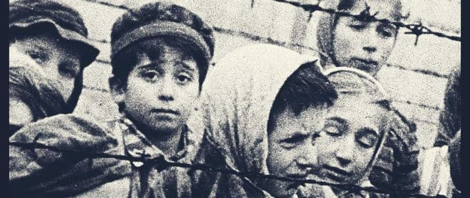 photograph of a woman and children looking out from behind barbed wire