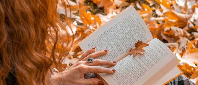 woman reads a book against a background of foliage