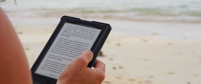 person reading an e-reader on the beach